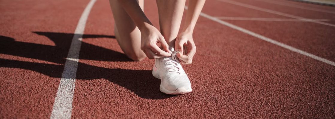 Close-up of a woman tying her shoes on a running track, ready to sprint.