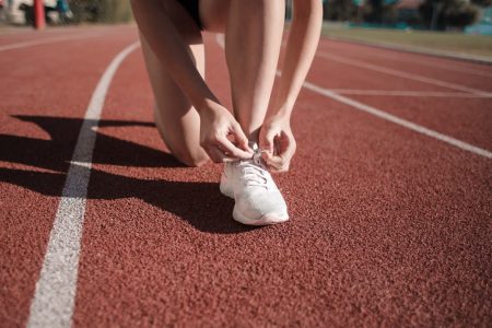 Close-up of a woman tying her shoes on a running track, ready to sprint.